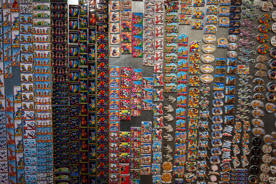 Full frame view of a wall covered in hundreds of colourful, traditional ceramic and painted fridge magnets from a souvenir shop.
