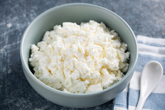 Curd cheese (tvorog) in blue ceramic bowl. Rich in calcium and protein dairy product