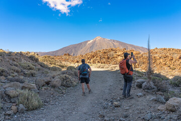 Fototapeta premium Two men with backpacks are observing the surroundings in Teide National Park. Tenerife. Canary Islands.