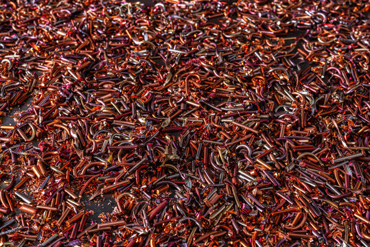 Copper scraps and shavings showing color change caused by heat and oxidation, used as raw material for non-ferrous metal recycling industry.