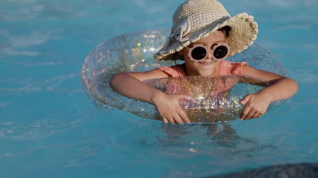Cute funny toddler girl relaxing on inflatable toy ring floating in pool have fun during summer vacation. Child having fun in swimming pool. 