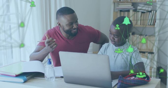 In this image, an african american father is helping his son with homework while sitting at a table