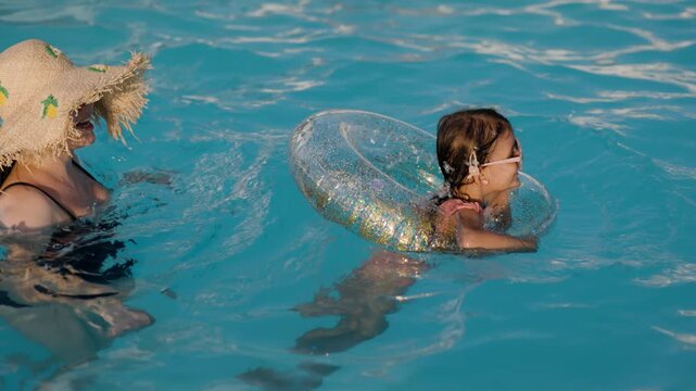 mom and daughter in pool have fun during summer vacation. Child having fun in swimming pool. 