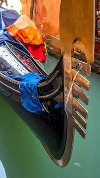 Gondola prow detail metal decoration, reflections in canal water, blue fabric and orange cover