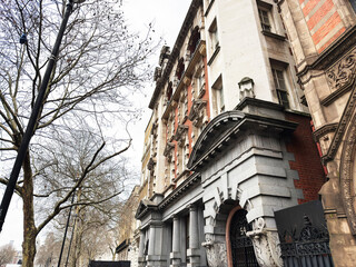 Fototapeta premium Historic stone and brick architecture on a London, UK street with ornate entrance and bare trees