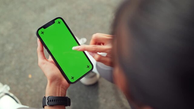 Hand of sports woman holding smartphone with green screen for copy space, mobile fitness app technology for health and workout training, space for advertising