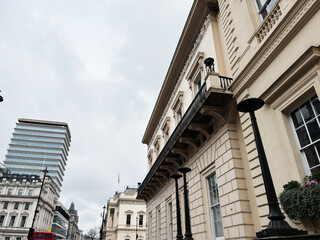 Fototapeta premium Neoclassical building facade and city street with red bus in London, UK on overcast day