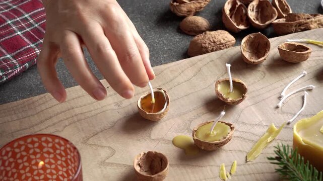 Making homemade Christmas candles from walnut shells and beeswax - inserting the wick
