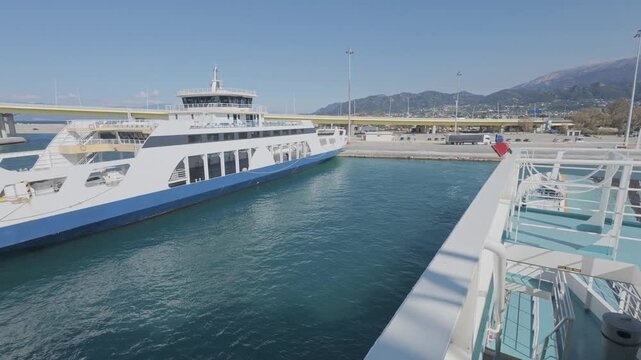 Port scene with ferry departing and anchored ro-ro ship in background