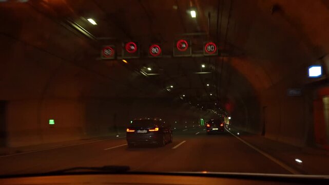 JENA, GERMANY - MARCH 27, 2026: POV driving through a highway tunnel near Jena with moving traffic, illuminated tunnel interior and road infrastructure in warm artificial light.