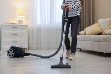 Fototapeta premium Teenage girl cleaning floor with vacuum cleaner at home, closeup