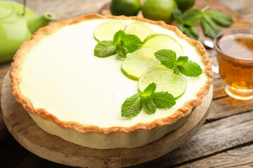 Tasty lime pie with fruit slices and mint leaves on wooden table, closeup © New Africa