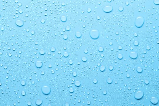 Many water drops on light blue background, top view