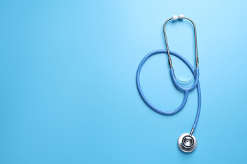 Fototapeta premium One stethoscope on light blue background, top view. Space for text