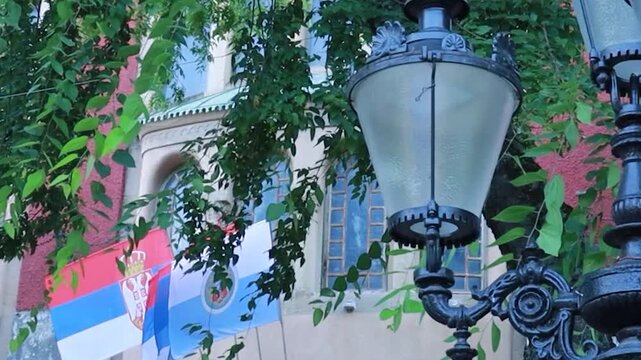 Vintage Street Lamp with Blurred Serbian Flag on City Hall Building