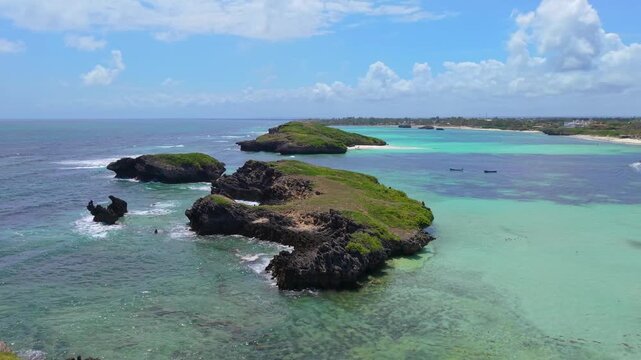 Aerial view of rocky islets and turquoise ocean water along the coastline with white sand and coral reefs at Watamu Beach, Kenya.