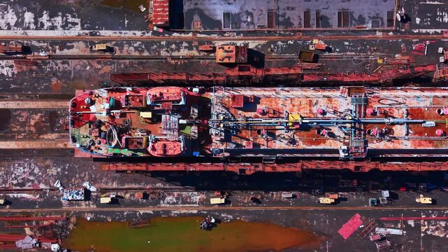 Weathered ship deck featuring complex piping systems, hatches, and safety equipment in a shipyard. Top view of industrial tanker deck with pipes and valves.