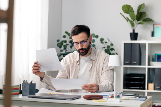 Man in glasses reviewing business documents at home office