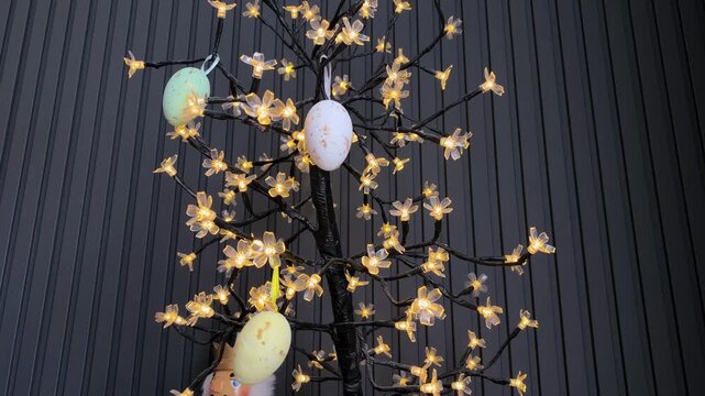 Woman's hands decorating luminous easter egg tree