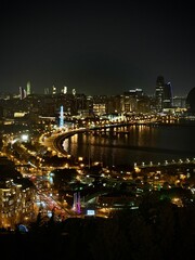 Fototapeta premium Night waterfront skyline with curving boulevard lights, conveying urban glamour, travel romance, city energy, and evening tourism atmosphere.