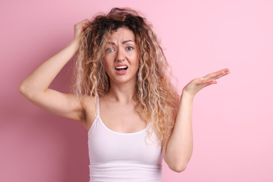 Unhappy woman with tangled hair on pink background