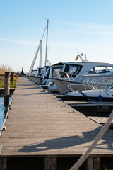 Fototapeta premium Sunny Marina Scene with Moored Boats and Wooden Pier Under a Clear Blue Sky, Inviting Serene Waterside Leisure