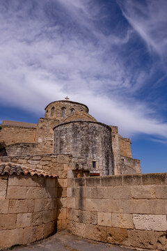 Historic exterior view of the Monastery of Saint Barnabas in Famagusta, Northern Cyprus, showcasing ancient stone architecture, a domed church, and dramatic sky.


