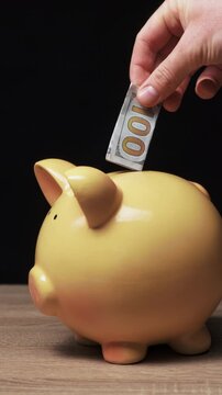 Hand Placing Cash Into Piggy Bank, Closeup Of Adult Hand Inserting Folded Banknote Into Yellow Ceramic Pig