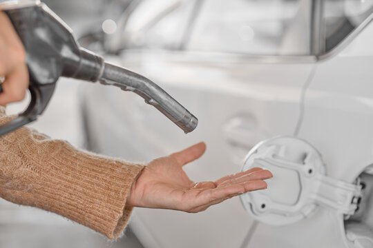 Person checking a fuel pump nozzle with hand, expecting gasoline but no fuel flows. Concept image illustrating fuel shortage, empty gas station supply, energy crisis and lack of petrol.