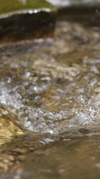Vertical Super Slow Motion of Sun-Drenched River Water Splashing. Macro Close-up of Sparkling Liquid Drops Of The River Water - Cinematic Nature and Luxury Wellness Concept.