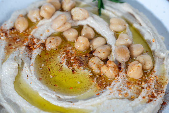 Hummus on a wood cutting board with cucumbers, peppers, pita chips and olive oil 