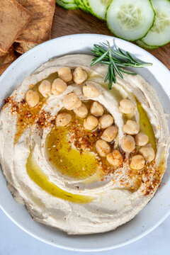 Hummus on a wood cutting board with cucumbers, peppers, pita chips and olive oil 