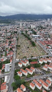 Drone mostra cemit&eacute;rio com t&uacute;mulos organizados e &aacute;rea urbana ao redor destacando espa&ccedil;o funer&aacute;rio e estrutura urbana em Mogi das Cruzes