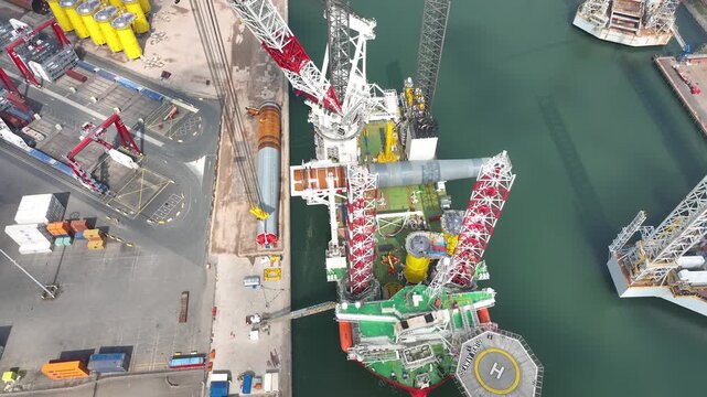 Rotterdam, Netherlands. Drone flight over industrial area with cargo ports, containers and a semi-submersible ship, heavy lifting crane. Machines designed for work at sea
