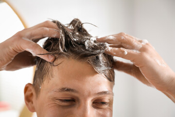 Naklejka premium Man washing his hair with shampoo in bathroom, closeup