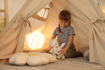 Little girl playing with toys in wigwam at home © New Africa