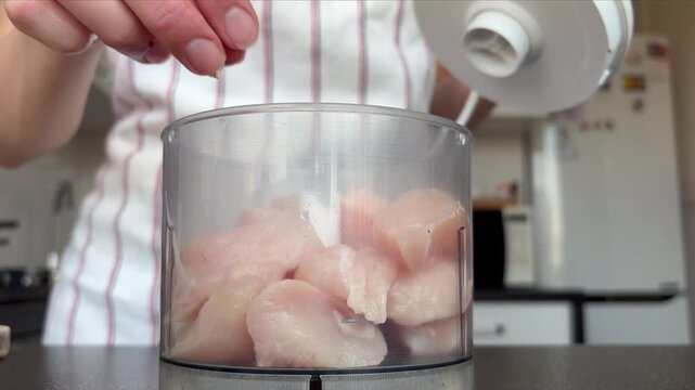 A woman prepares chicken pate using a hand blender in her kitchen at home.
