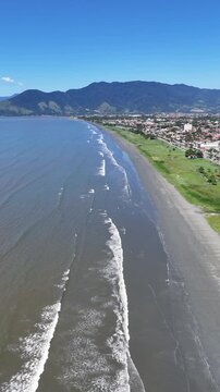 Vista a&eacute;rea da Praia do Porto Novo mostrando extens&atilde;o da costa, mar e vegeta&ccedil;&atilde;o, representando destino tur&iacute;stico e natureza no litoral norte de S&atilde;o Paulo