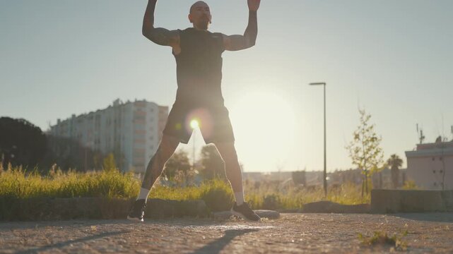 Tattooed athlete man doing jumping jacks outdoor workout