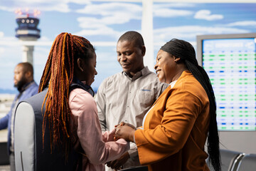 Sad mother and father saying farewell to their teenage daughter at airport, offering guidance before boarding airplane alone. Emotional family bond with young girl traveling as foreign student. © DC Studio