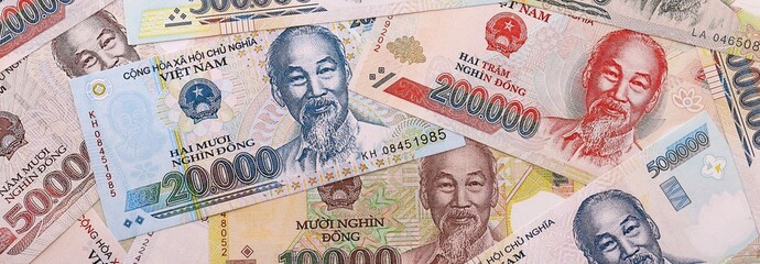 Obraz premium Vietnamese dong money bills pile on table. Vietnam banknotes of VND currency close up.