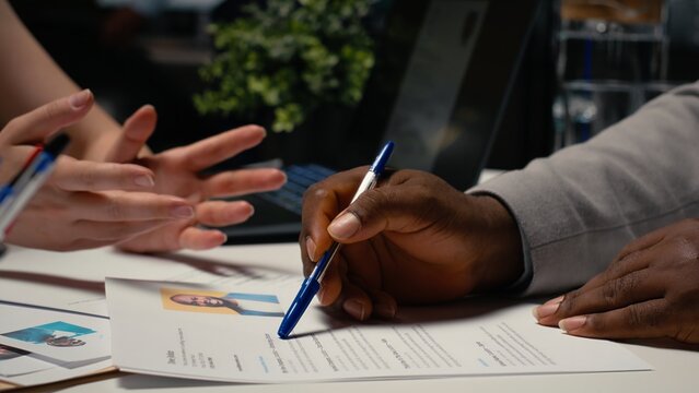 Close up of a CV resume on the table during detailed job interview with applicant and HR manager, reviewing the candidate qualifications and work experience for the selection process. Camera B.