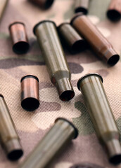 Fototapeta premium Big amount of shells cartridges from assault rifle bullets on old camouflage fabric