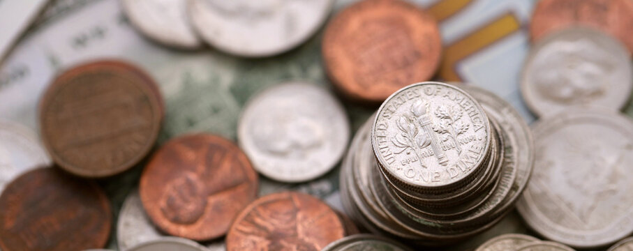 Big amount of United States coins on hundred dollar money bills arranged in chaotic order