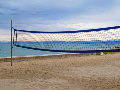 Beach volleyball net on empty seaside court with dramatic cloudy sky and ocean view