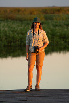 Woman birdwatching with binoculars at sunset outdoors
