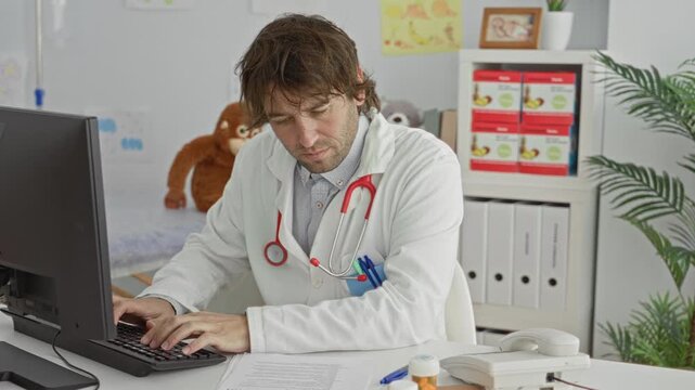 Man doctor types on keyboard with hands on keys at desktop computer, stethoscope draped on neck in clinic building; professional concentration.
