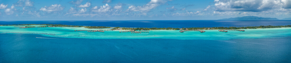 Fototapeta premium panoramic aerial landscape view of parts of Piti Aau and Motu Piti A'au Atoll as part of Bora Bora island with resorts and bungalows in bright turquoise blue water and Taha'a Island in the background 