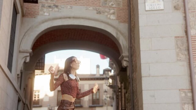 Happy young woman dancing listening to music in the street