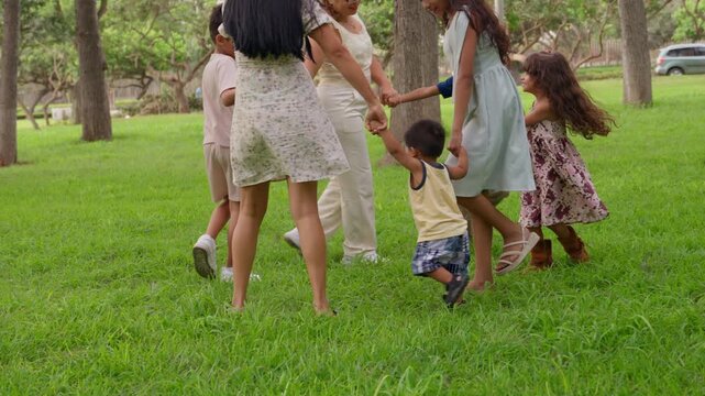 Happy latin family playing and dancing in a circle at the park